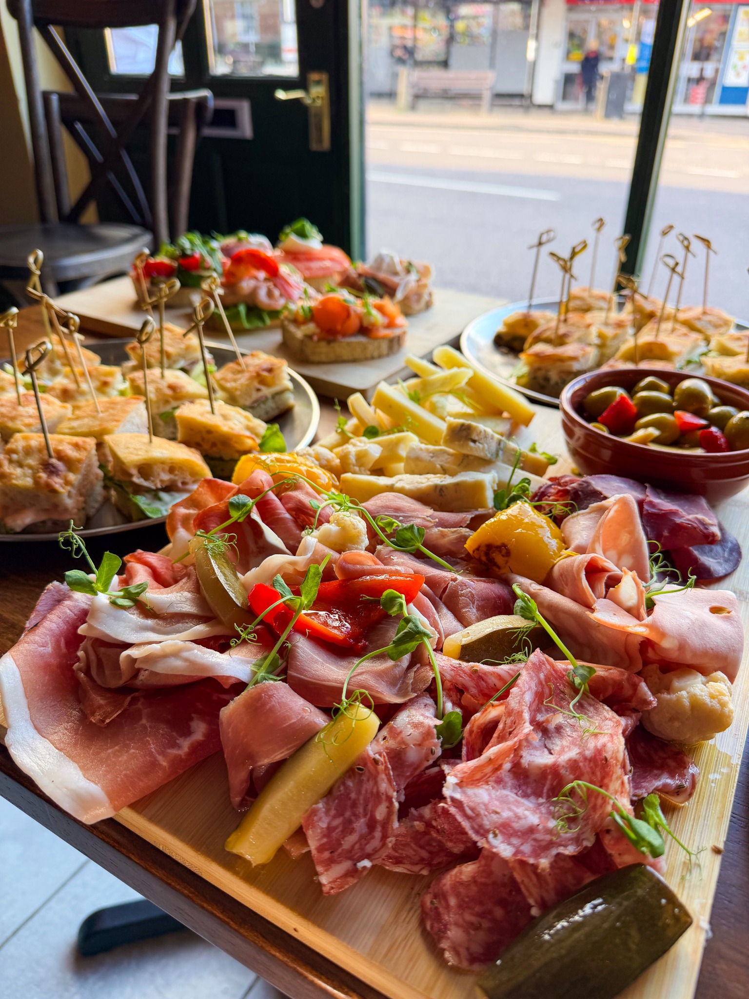 Charcuterie and cheese with focaccia and open sandwiches behind