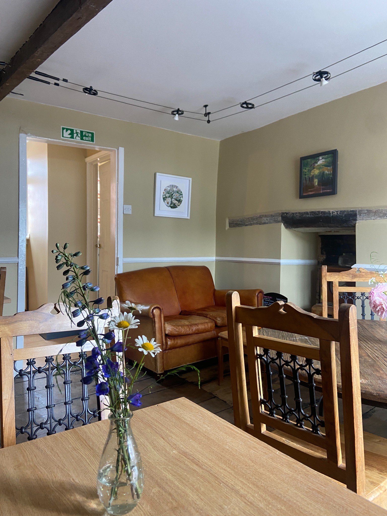 Flowers on a wooden table in Otto’s private dining room, with timber beams, a fireplace and seating